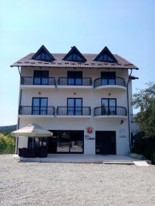 un gran edificio blanco con una sombrilla delante en Pensiunea Clasic, en Curtea de Argeş