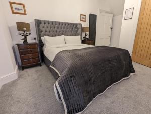 a bedroom with a large bed with a gray blanket at Cambeth Lodge in Inverness