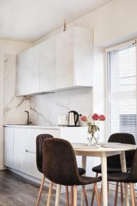 a white kitchen with a table and chairs at Owls Hill Apartment in Kaunas