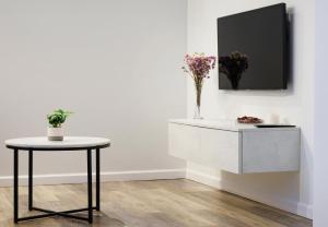 a white table and a table with flowers on a wall at Owls Hill Apartment in Kaunas +18 photos