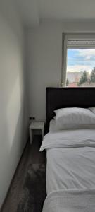 a white bedroom with a bed and a window at Perfect Place 33 in Varaždin