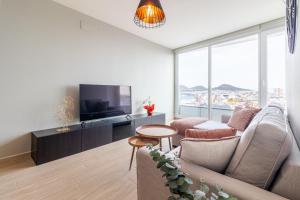 a living room with a couch and a tv at Brand New Apartment with Ocean & Volcano Views in Las Palmas de Gran Canaria