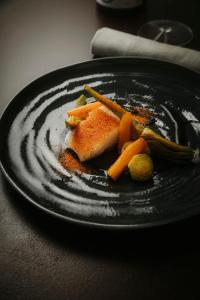 a black plate of food with carrots on a table at La Dama del Porto in Laveno-Mombello +30 photos