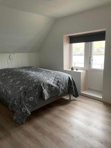 a bedroom with a bed with a black comforter and a window at The house with the amazing view in Sørvágur