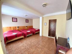 three beds in a room with red sheets at Hotel Nakbé Atitlán in Panajachel