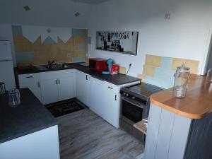 a kitchen with white cabinets and black counter tops at Grand Duplex, 6 personnes in Besse-et-Saint-Anastaise