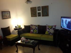 un soggiorno con divano verde e TV di Two-Bedroom Chalet at Blumar Wadi Degla Sidi Abdel Rahman a El Alamein
