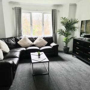 a living room with a leather couch and a coffee table at Levenside Holiday Apartment, Balloch, Loch Lomond in Balloch