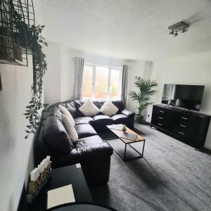 a living room with a leather couch and a tv at Levenside Holiday Apartment, Balloch, Loch Lomond in Balloch