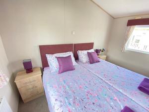 a bedroom with a large bed with purple sheets and pillows at Lavender Lodge, Accessible in South Cerney +42 photos