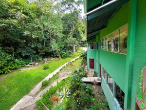 una casa verde con un jardín al aire libre en La Casa de la Montaña, en Monteverde
