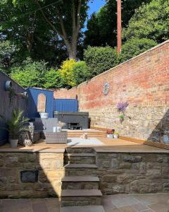a backyard with a brick wall and a bench and stairs at Rose Cottage in Morpeth