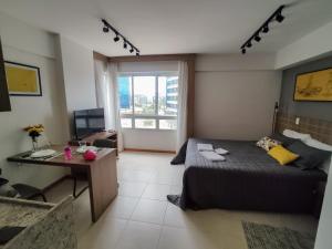 a bedroom with a bed and a desk and a window at Saint Moritz. Apartamento charmoso no centro de Brasília. in Brasilia