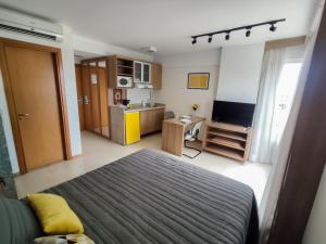 a bedroom with a bed and a tv and a kitchen at Saint Moritz. Apartamento charmoso no centro de Brasília. in Brasilia