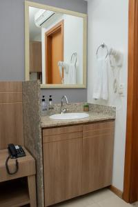 a bathroom with a sink and a mirror at Saint Moritz. Apartamento charmoso no centro de Brasília. in Brasilia