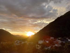 um pôr do sol sobre uma cidade nas montanhas em Cobertura das Montanhas em Domingos Martins