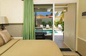 - une chambre avec un lit et une vue sur la piscine dans l'établissement Yoyita Suites Aruba Villa, à Palm-Eagle Beach