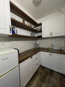 a kitchen with white cabinets and a sink at City Center Studio Apartment in Gjakove +6 photos