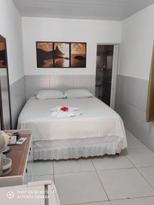 a bedroom with a white bed with a red flower on it at Pousada Mar de vênus in Fernando de Noronha