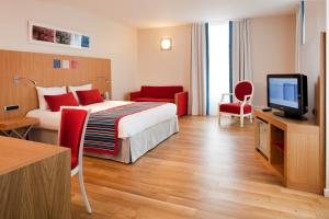 a hotel room with a bed and a flat screen tv at Hôtel Mercure Vittel in Vittel