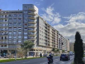 a large apartment building on a city street with a motorcycle at Aukera - Basque Stay in San Sebastián