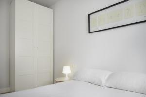 a white bedroom with a bed and a picture on the wall at Aukera - Basque Stay in San Sebastián