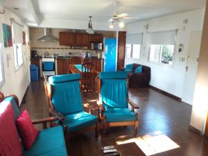 a living room with blue chairs and a kitchen at Casa Con Pileta En Roldan in Roldán