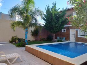 a swimming pool in a yard with two palm trees at Casa Con Pileta En Roldan in Roldán