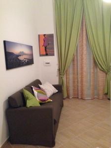 sala de estar con sofá y cortinas verdes en Appartamento Reginella, en Nápoles