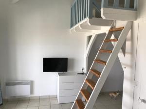 Cette chambre dispose d'un escalier blanc et d'une télévision. dans l'établissement Appartement cosy en résidence privée avec vue mer, à Soulac-sur-Mer
