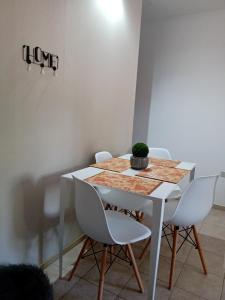 une table blanche avec des chaises blanches et une plante sur celle-ci dans l'établissement Cálido Departamento y Estacionamiento Gratuito, à Godoy Cruz