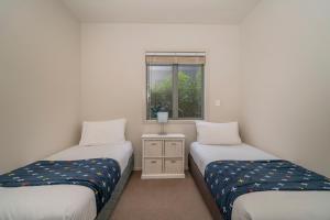 two twin beds in a room with a window at Matarangi Lakeside Gem - Golfers Dream! in Matarangi