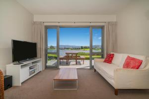 a living room with a couch and a flat screen tv at Matarangi Lakeside Gem - Golfers Dream! in Matarangi