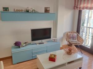 un salon avec une télévision sur un meuble bleu dans l'établissement maravilloso apartamento en la playa...muy especial, à Sanxenxo