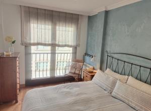 - une chambre avec un lit, une chaise et des fenêtres dans l'établissement maravilloso apartamento en la playa...muy especial, à Sanxenxo