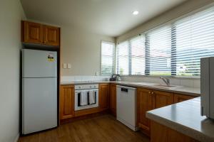 a kitchen with a white refrigerator and wooden cabinets at *** LAKE VILLA 459 *** in Hanmer Springs
