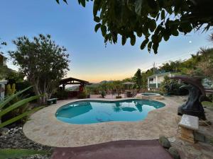 una piscina en un patio con jardines en Pancho's Paradise - Rainforest Guesthouse with Pool, Gazebo and View, en Canovanas