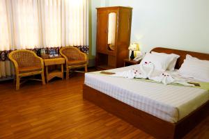 1 dormitorio con 1 cama, mesa y sillas en Sandalwood Hotel, en Nyaung Shwe