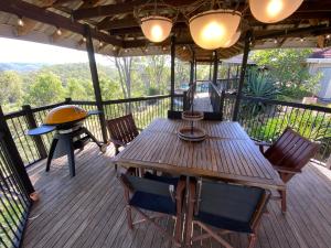 una terraza de madera con mesa y sillas de madera en KooralBnB, en Kooralbyn