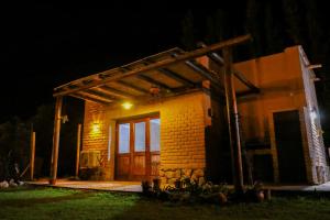 uma pequena casa com uma porta de madeira à noite em Pasillos del Viñedo em Cafayate