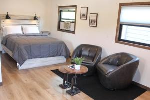ein Schlafzimmer mit einem Bett und zwei Ledersesseln in der Unterkunft Cabin 4 at Horse Creek Resort in Rapid City