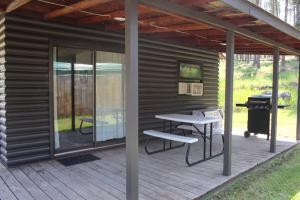 a screened in porch with a picnic table and a grill at Cabin 5 at Horse Creek Resort in Rapid City