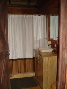 a bathroom with a sink and a white shower curtain at Log Cabin in Tinamaste Valley, Habacuc Woods, BARÚ in Platanillo