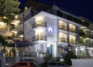 a white building with cars parked in front of it at Hotel Azimut in Sveti Stefan