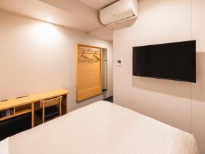 a bedroom with a bed and a flat screen tv at Sotetsu Fresa Inn Daimon in Tokyo