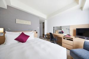 a hotel room with a bed and a desk and a tv at ANA Crowne Plaza Kanazawa by IHG in Kanazawa