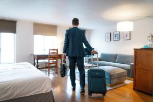 Ein Mann, der mit einem Koffer durch ein Hotelzimmer geht. in der Unterkunft Le Sauvage in Freiburg im Üechtland