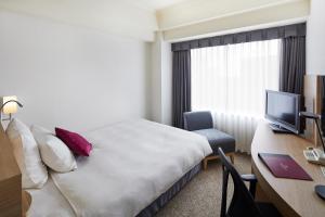 a hotel room with a bed and a desk with a computer at ANA Crowne Plaza Kanazawa by IHG in Kanazawa