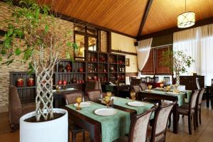 un restaurante con mesas, sillas y una planta en Грейс Абрис, en Adler