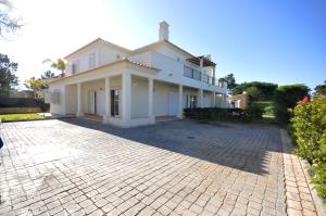 een groot wit huis met een stenen oprit bij Large 6 bedroom private pool villa in Vilasol Resort in Quarteira